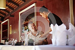 Asian waitress talking with client in restaurant