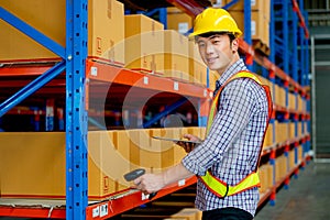 Asian warehouse worker hold barcode scaner and tablet and look at camera with smiling