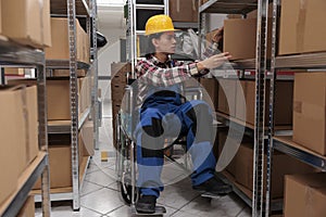 Asian warehouse worker in wheelchair taking parcel from shelf