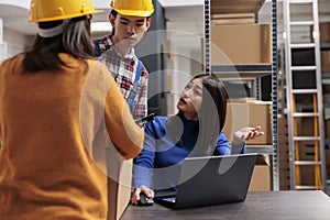 Asian warehouse workers team doing inventory tracking on laptop