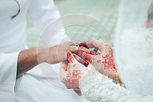 An asian wedding ceremony, the bride give the wedding ring to the groom.