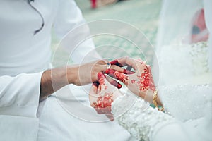 An asian wedding ceremony, the bride give the wedding ring to the groom.