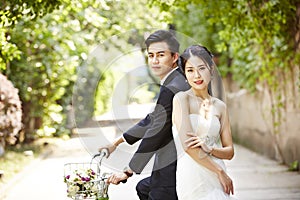 Asian wedding couple riding bicycle