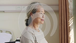 Asian wheelchair bound old woman turning to camera smiling