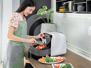 Asian wife cooking fries chicken by use her electric fryer in her kitchen at home