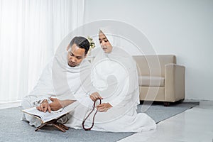 Asian wife and husband praying with Al-Qur`an and tasbih photo