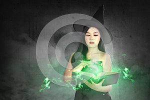 Asian witch woman in hat learns the spell from the magic book