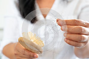 Asian woma holding hairbrush with many hair fall