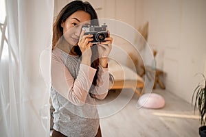 Asian woma taking pictures with old film camera. woman Photographer making pictures with retro camera having fun at home.