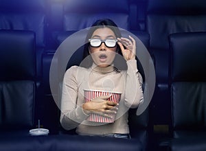 Asian woman in 3D glasses watching horror movie in cinema