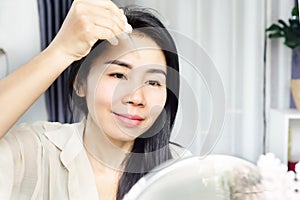 Asian woman age 40s applying serum collagen on her skin face, forehead for anti-aging and winkles