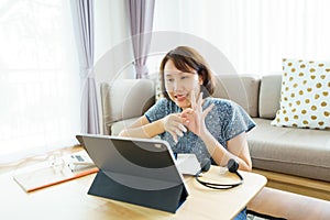 Asian woman aged 30-35 years using tablet, watching lesson Sign language online course communicate by conference video call from