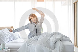 An Asian woman aged about 20 wakes up in the morning in a bright bed in a bedroom or hotel After a restful night`s sleep photo