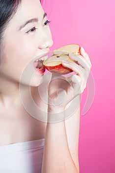 Asian woman with apple concept. She smiling and holding apple. Beauty face and natural makeup. Isolated over pink background.