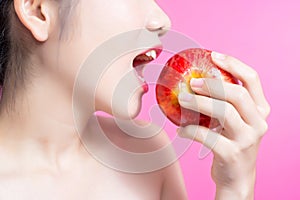 Asian woman with apple concept. She smiling and holding apple. Beauty face and natural makeup. Isolated over pink background.