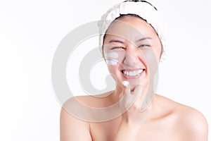 Asian woman apply cream, lotion to beautiful skin on face, smile face. Young woman show cream, apply moisturizer on face. Asia bea