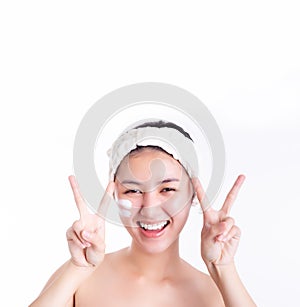 Asian woman apply cream, lotion to skin on face after bath. Pretty young asian girl make sign of victory by using fingers make sym