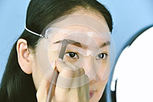 Asian woman applying cosmetics makeup, Eyebrows template head strap use for shaping.