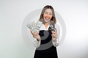 Asian woman in apron posing holding cash money in dollar and credit card