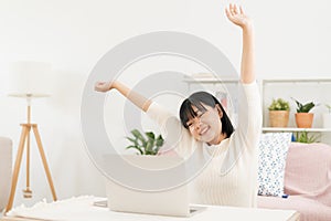 Asian woman arms stretched and working at home. Asia teen using laptop while sitting in living room at morning