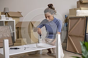 Asian woman is assembling furniture after moving into a new house