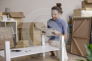 Asian woman is assembling furniture after moving into a new house