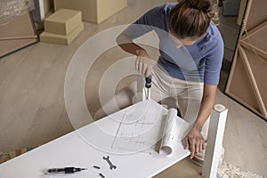 Asian woman is assembling furniture after moving into a new house