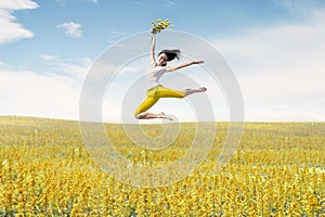 Asian woman ballerina holds bouquet of flowers making a big jump on meadow.