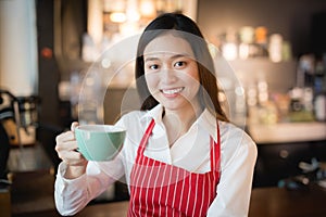Asian woman barista smiling with a cup of coffee in her hand,Coffee salesmen deliver coffee to customers,vintage filter effect