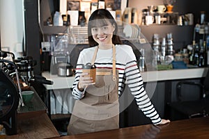 Asian woman barista standing smiling with a cup of coffee in her