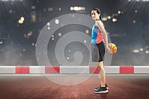 Asian woman basketball player holding the ball on her back