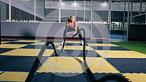 Asian woman with battle ropes exercise in the fitness gym