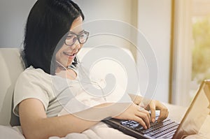 Asian woman be happy and smile with her laptop and earpieces.