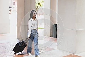 Asian woman beaming carrying a suitcase black to travel on vacation, Trolley bag