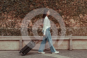 Asian woman beaming carrying a suitcase black to travel on vacation, Trolley bag