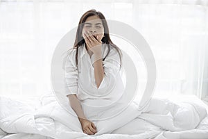 Asian woman Beautiful young smiling woman sitting on bed and stretching in the morning at bedroom after waking up in her bed full