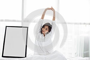 Asian woman Beautiful young smiling woman sitting on bed and stretching in the morning at bedroom after waking up in her bed fully
