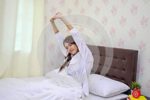 Asian woman Beautiful young smiling woman sitting on bed and stretching in the morning at bedroom after waking up in her bed fully