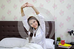 Asian woman Beautiful young smiling woman sitting on bed and stretching in the morning at bedroom after waking up in her bed fully