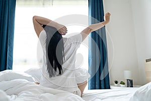 Asian woman Beautiful young stretching in the morning at bedroom after waking up in her bed fully rested