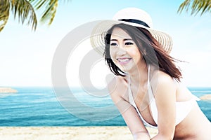 Asian woman with bikini and hat relaxing on the beach