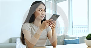 Asian woman blab on speakerphone sit at desk with cellphone