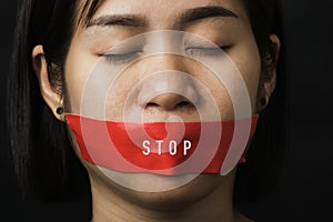 Asian woman blindfold wrapping mouth with red adhesive tape