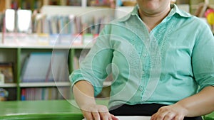 Asian woman with blindness disability moving hands using fingers reading Braille book studying in creative workplace library.