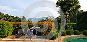 Asian woman in blue women\'s exercise clothes doing yoga beside pool in the morning