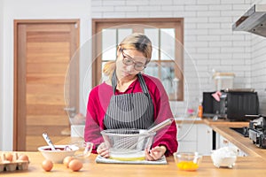 Asian woman is bored to cook chocolate cake in modern kitchen room