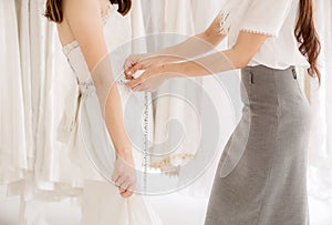 Asian woman bride trying on wedding dress,Women tailor making adjustment with measuring tape,Close up