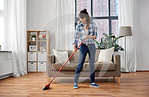 Asian woman with broom sweeping floor and cleaning