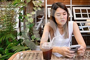 Asian woman browse social media in mobile, feeling sad and depress.