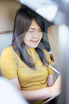 Asian woman business sitting in car and making note or working